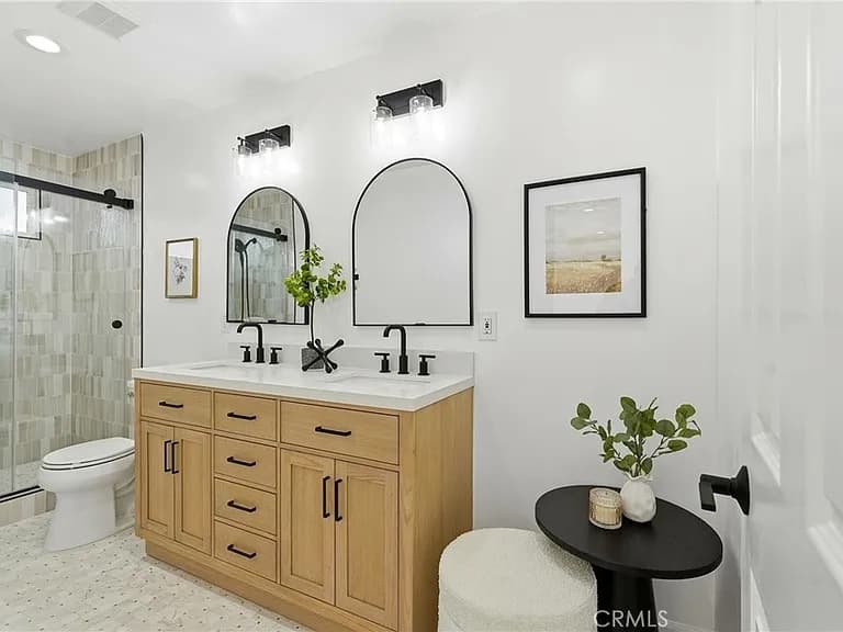 Renovated bathroom with a double oak vanity, arched mirrors and a tiled walk-in shower